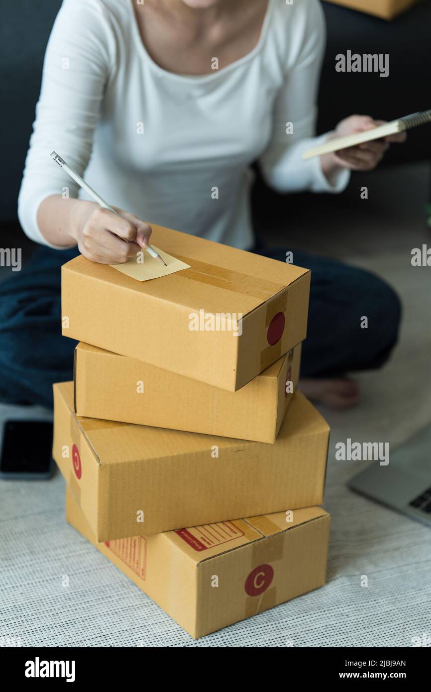 Donna asiatica, dipendente di e-commerce freelance con pacco da consegnare al cliente. Concetto di consegna della scatola di imballaggio in linea di vendita. Foto Stock