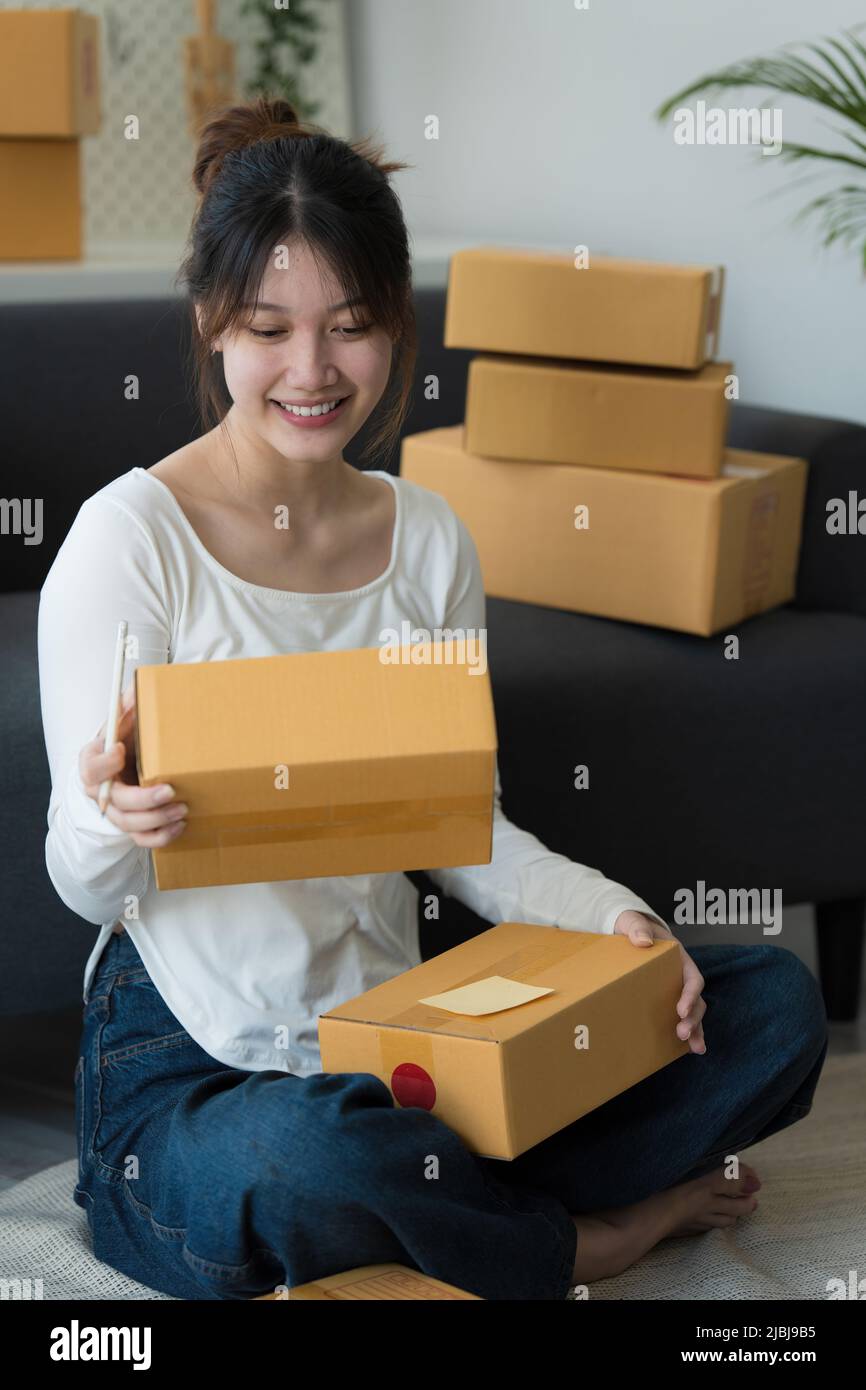 Un ritratto di donna asiatica, dipendente e-commerce freelance con pacco da consegnare al cliente. Concetto di consegna della scatola di imballaggio in linea di vendita. Foto Stock