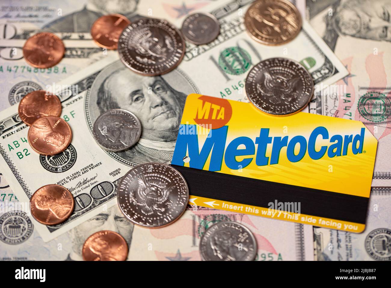 Manhattan, New York/USA - Aprile 8. 2021: Metrocard su banconote in dollari e monete in dollari statunitensi. Costo del trasporto pubblico a NYC. Biglietto per metropolitana e autobus. Foto Stock