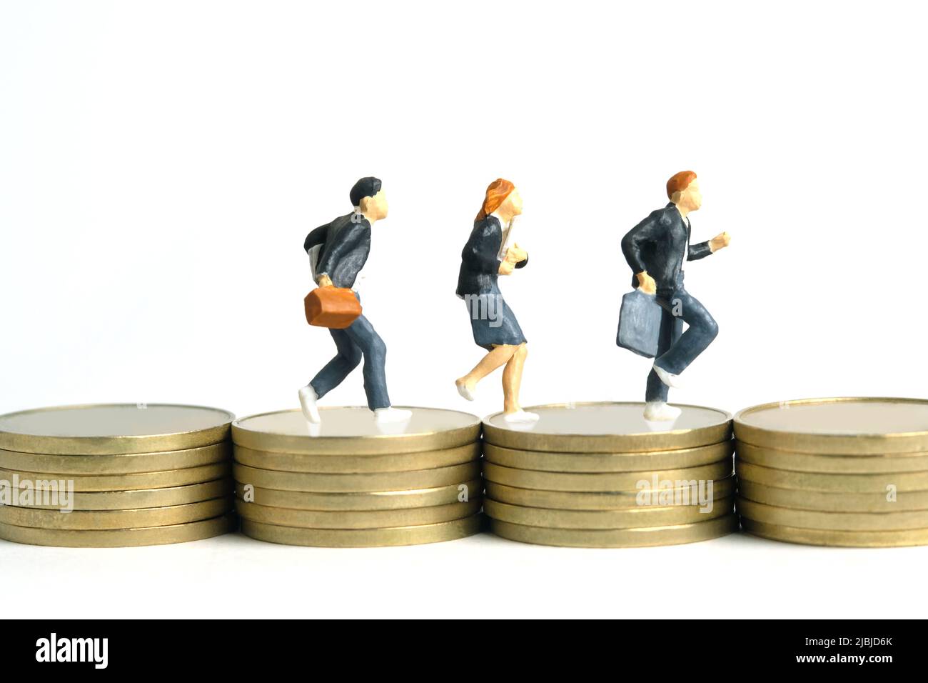 Fotografia di personaggi giocattolo in miniatura. Concetto di budget per l'ingresso alla scuola. Gli allievi che corrono sopra la moneta dorata impilano il denaro del cent, isolato sul backgro bianco Foto Stock