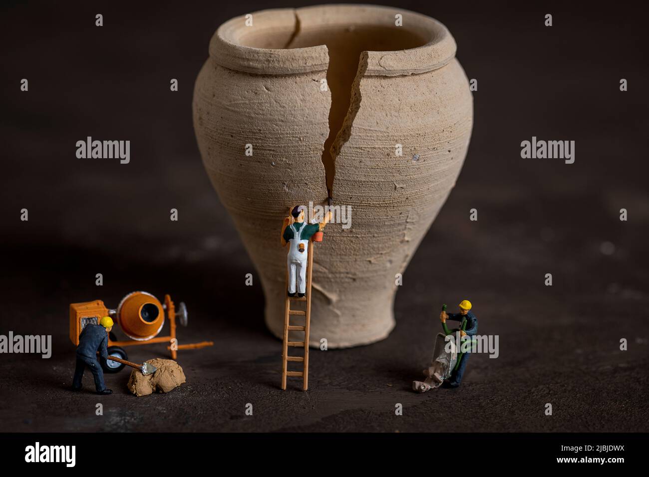 Persone in miniatura piccolo modello umano riparazione vecchio vaso d'acqua Foto Stock