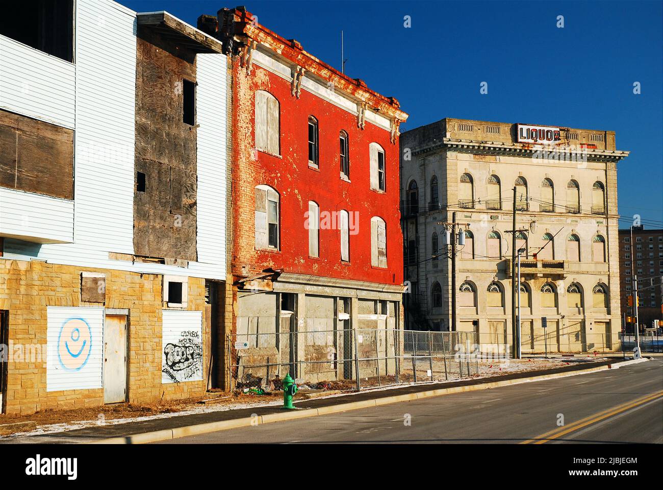 Edifici abbandonati e fatiscenti costeggiano una strada cittadina che mostra gli effetti del degrado urbano Foto Stock