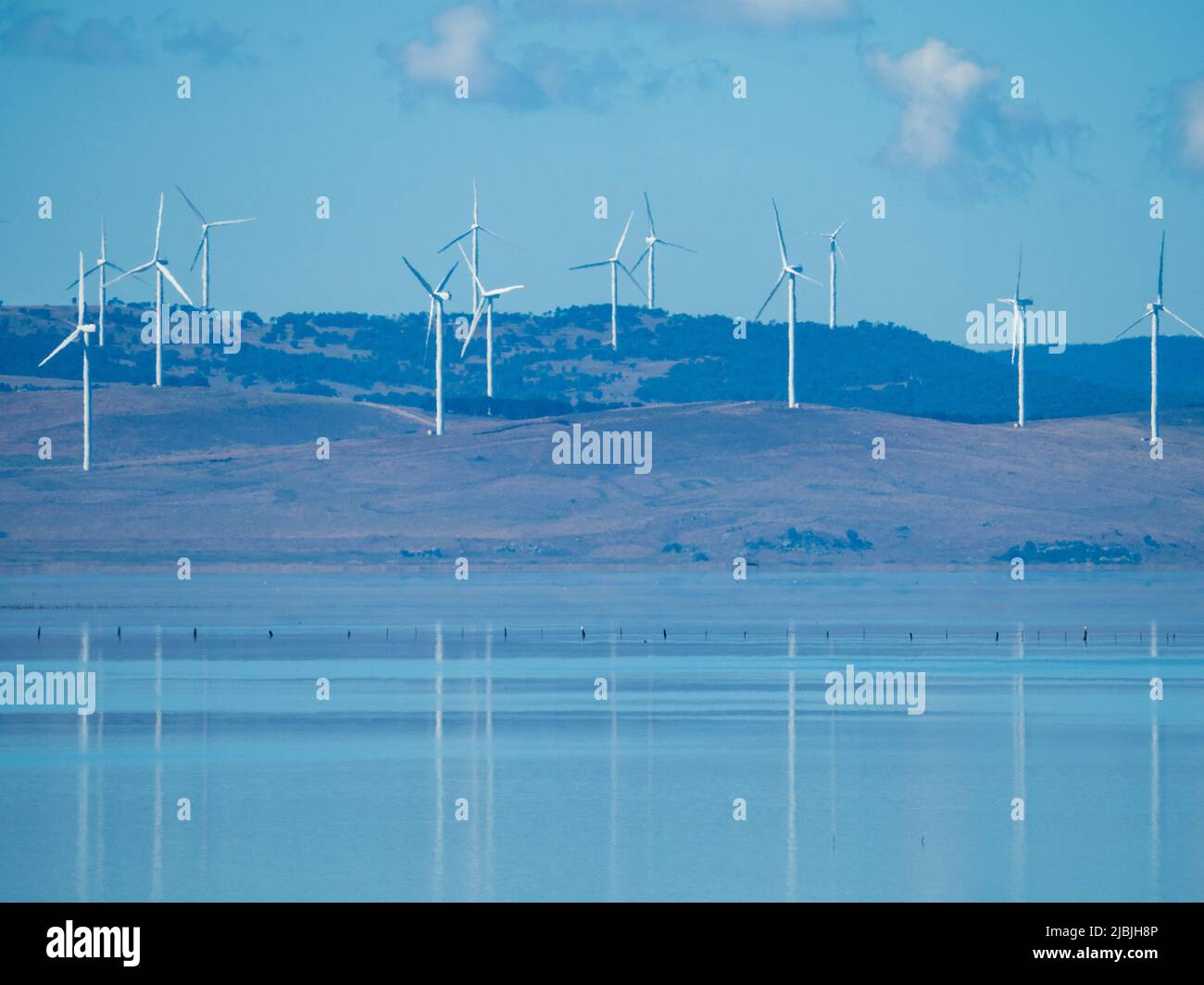 Mulini a vento o turbine eoliche prominenti sulla collina riflesse nelle acque lucide del lago George vicino alla capitale australiana Canberra ACT Australia Foto Stock