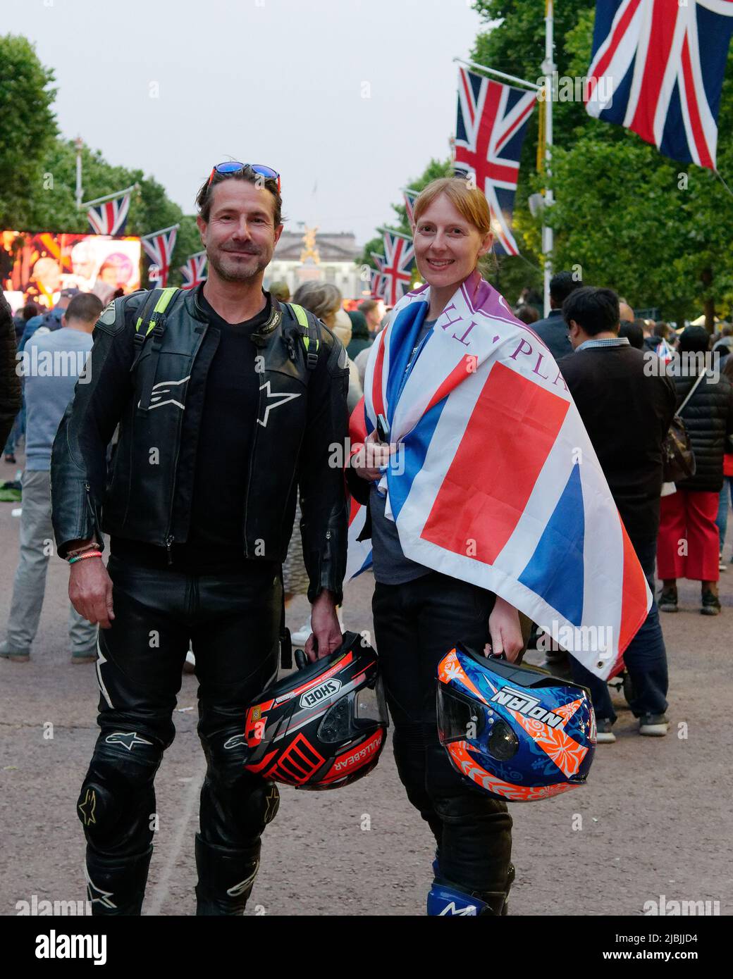Londra, Grande Londra, Inghilterra, 04 2022 giugno: Concerto Jubilee al Mall. Coppia in bicicletta tiene caschi e indossa una bandiera Union Jack. Foto Stock