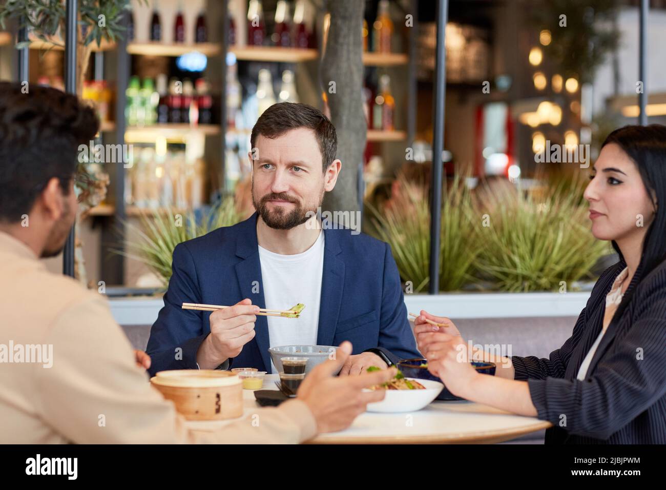 Gruppo di uomini d'affari che godono di cibo asiatico durante l'ora di pranzo d'affari nel caffè del centro commerciale Foto Stock