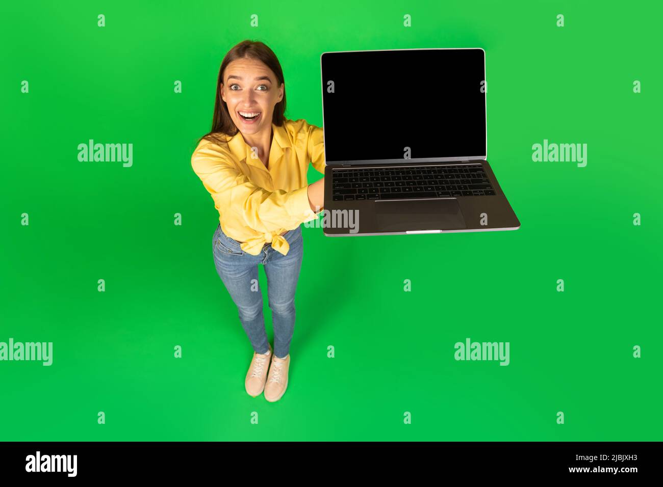 Signora che mostra schermo del laptop al sito Web di pubblicità della fotocamera, sfondo verde Foto Stock