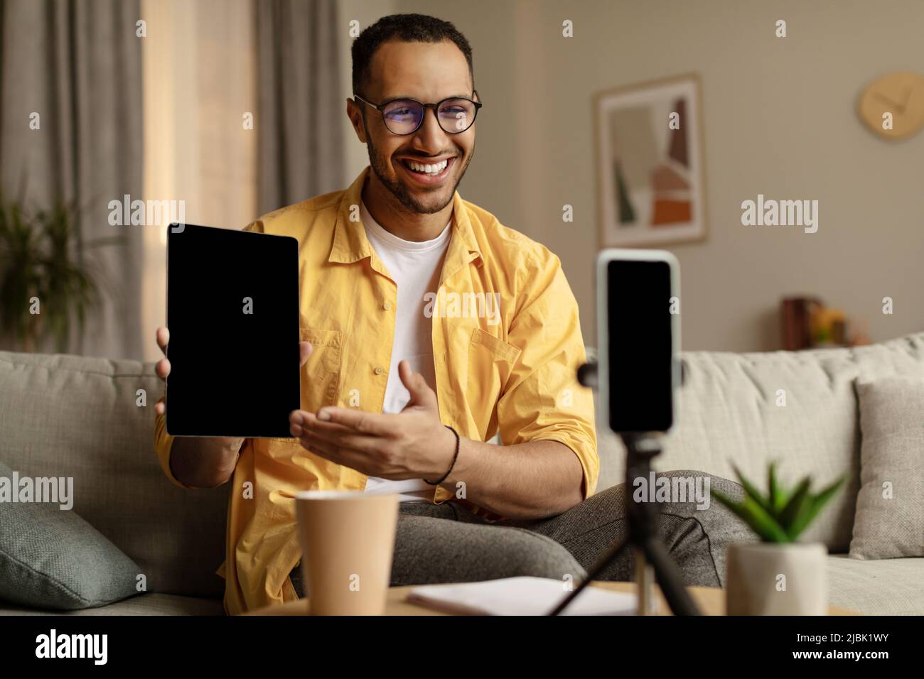 Happy nero maschio blogger filma video recensione di nuovo tablet computer sul cellulare a casa, mockup Foto Stock