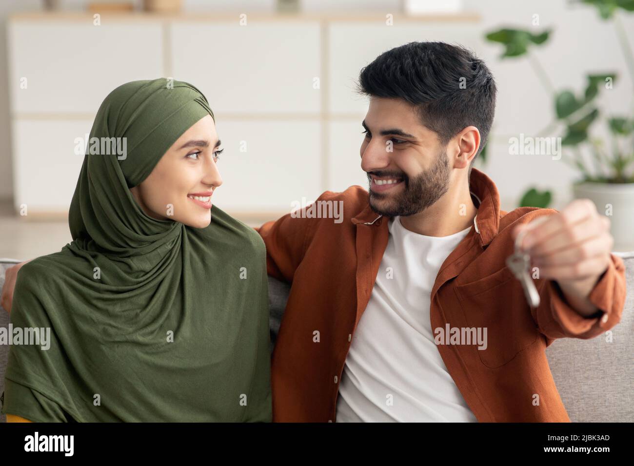 Gioiosa coppia mediorientale che tiene la chiave della nuova casa a casa Foto Stock