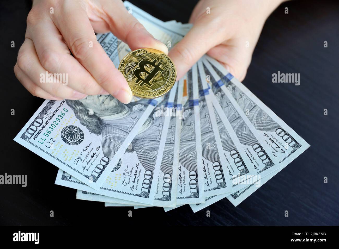 Banconote in Bitcoin e dollari statunitensi in mani femminili. Moneta decentralizzata elettronica, tasso di cambio e crescita della cripto-valuta Foto Stock