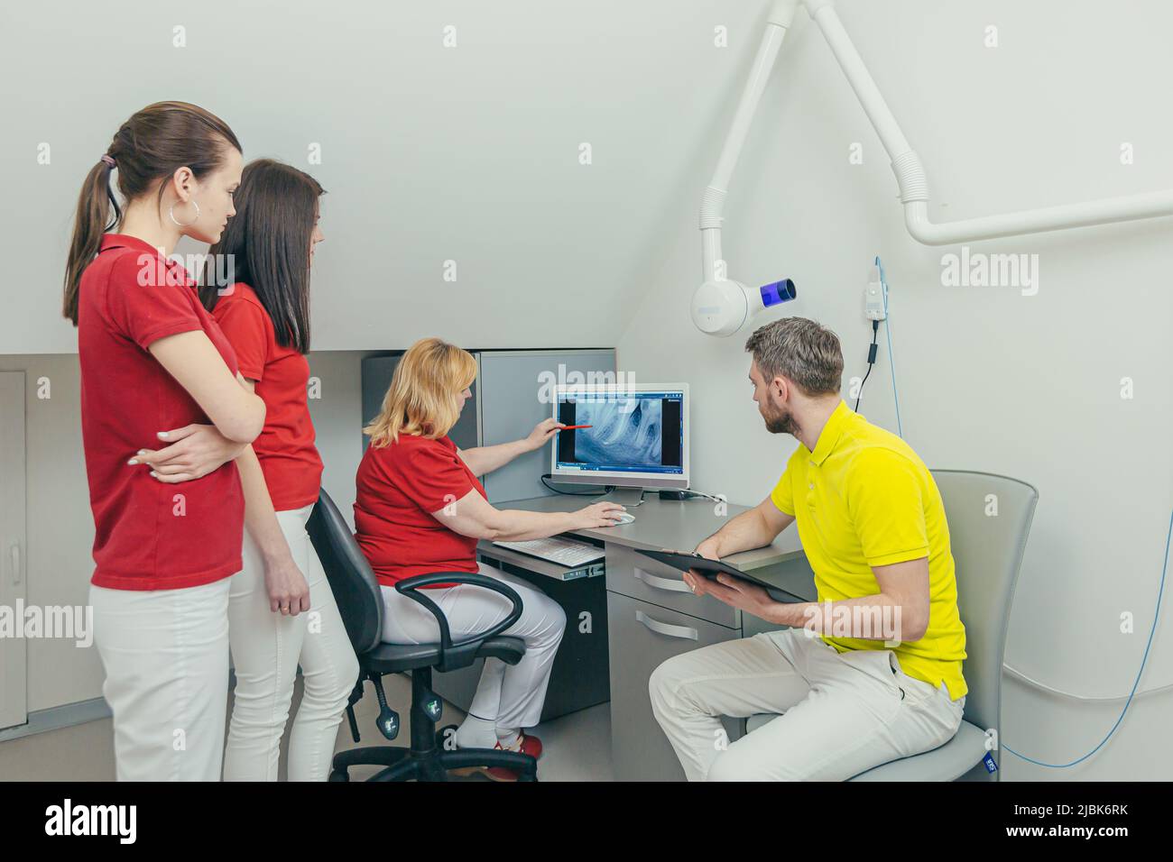 Incontro dei dentisti. Medici e assistenti esaminano i raggi X dei denti e delle mandibole del paziente sul computer, discutono il trattamento in ufficio Foto Stock