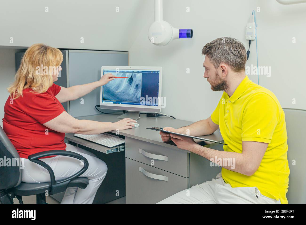 Incontro dei dentisti. Medici e assistenti esaminano i raggi X dei denti e delle mandibole del paziente sul computer, discutono il trattamento in ufficio Foto Stock