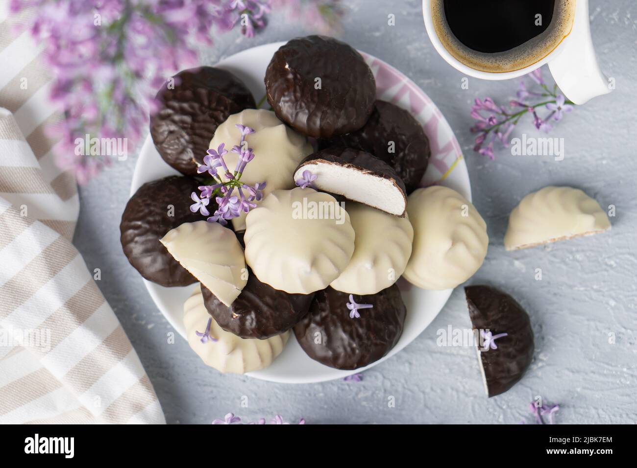 Tazza di caffè, lilla, marshmallow in glassa di cioccolato bianco e scuro. Dolce dessert al mattino Foto Stock