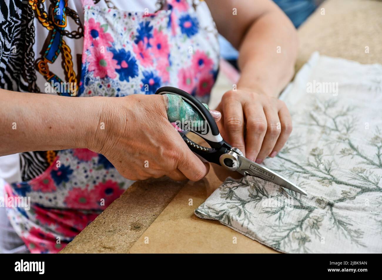 Non esclusiva: ZAPORIZHZHZHIA, UCRAINA - 3 GIUGNO 2022 - un volontario del Centro di Palianytsia taglia un pezzo di tessuto in strisce per fare le reti del camouflage Foto Stock
