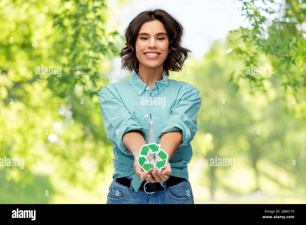 giovane donna sorridente che tiene il cartello verde di riciclaggio Foto Stock