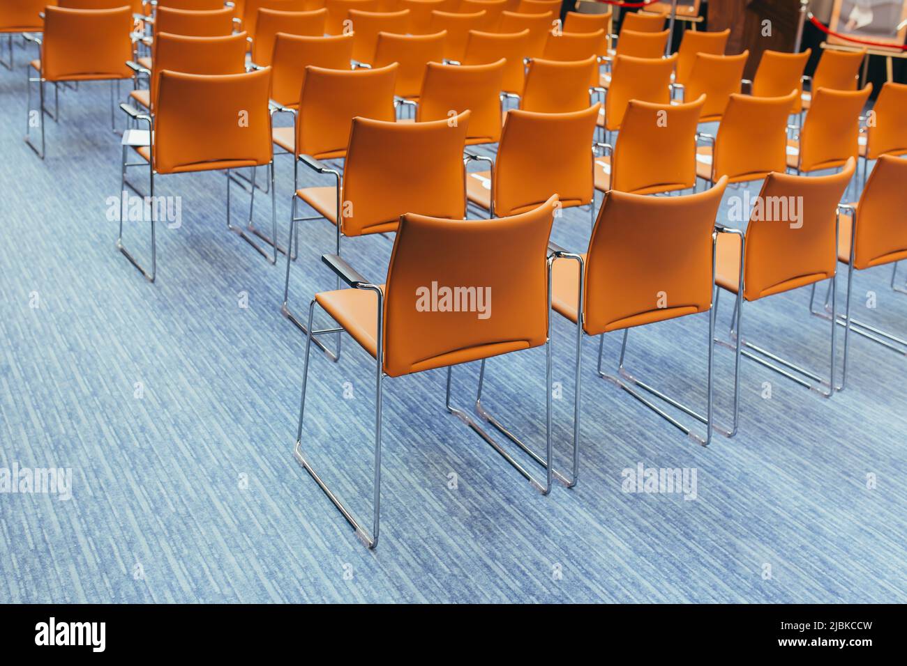 grande sala conferenze vuota con sedie arancioni prima dell'asta Foto Stock