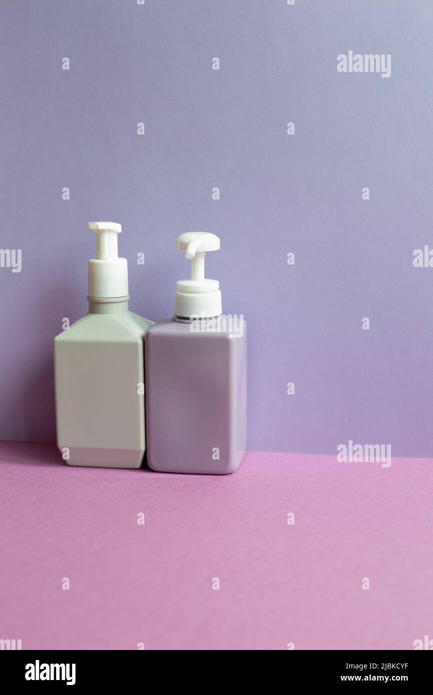 Bottiglie di shampoo in plastica su un tavolo viola. Fondo parete viola Foto Stock