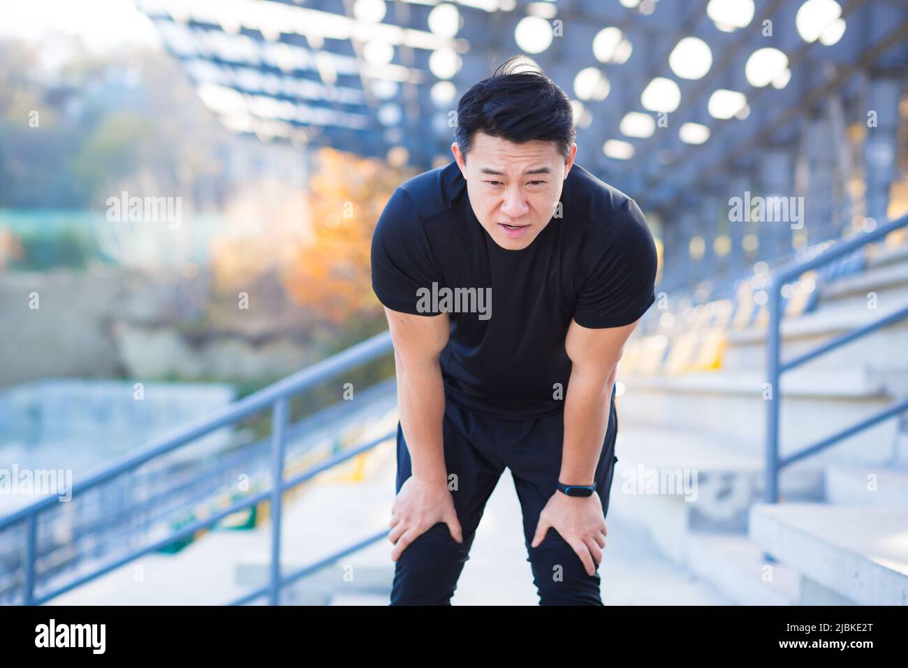 L'atleta asiatico ha una grave mancanza di respiro dopo l'allenamento, respira un battito cardiaco veloce, dopo l'allenamento Foto Stock