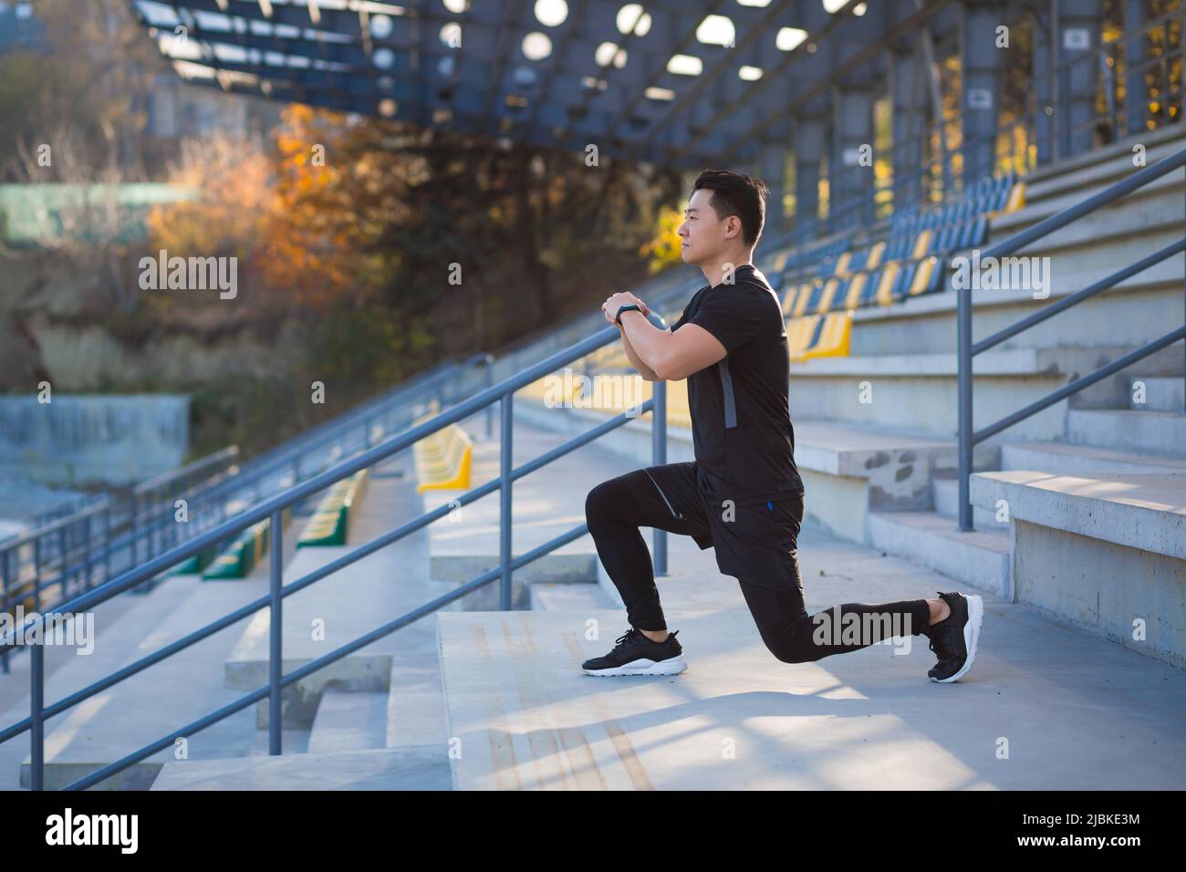 giovane uomo asiatico attivo fit impegnato in esercizio fisico che si estende strada all'aperto. Atleta maschile in allenamento sportivo Urban City Stadium Healthy Lifes Foto Stock