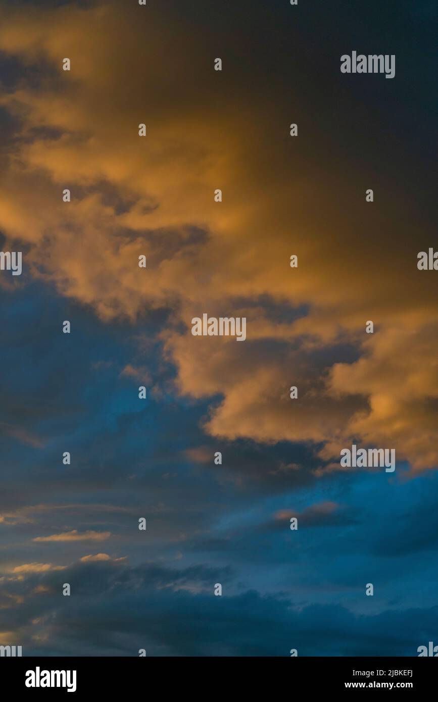 Beleuchtete Wolken beim Sonnenuntergang , mit starkem Kontrast der dunklen Wolken im Hintergrund dem dunkelblauen Himmel Foto Stock