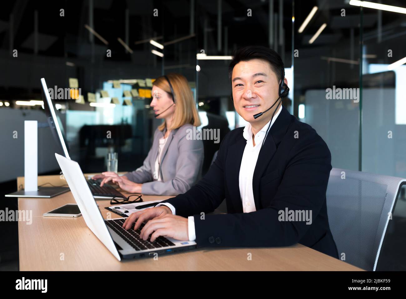 Uomo d'affari asiatico anziano maschio che lavora in ufficio, videochiamata, supporto tecnico guardando la macchina fotografica e sorridente dipendente di successo felice Foto Stock