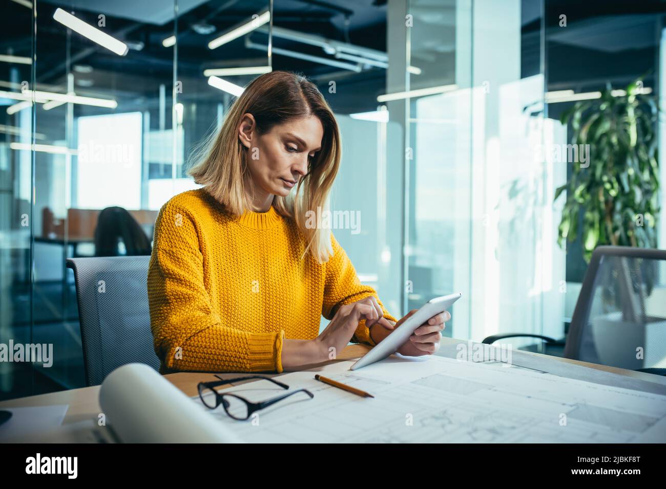 L'architetto professionista lavora in un ufficio moderno sui disegni, usa un tablet Foto Stock