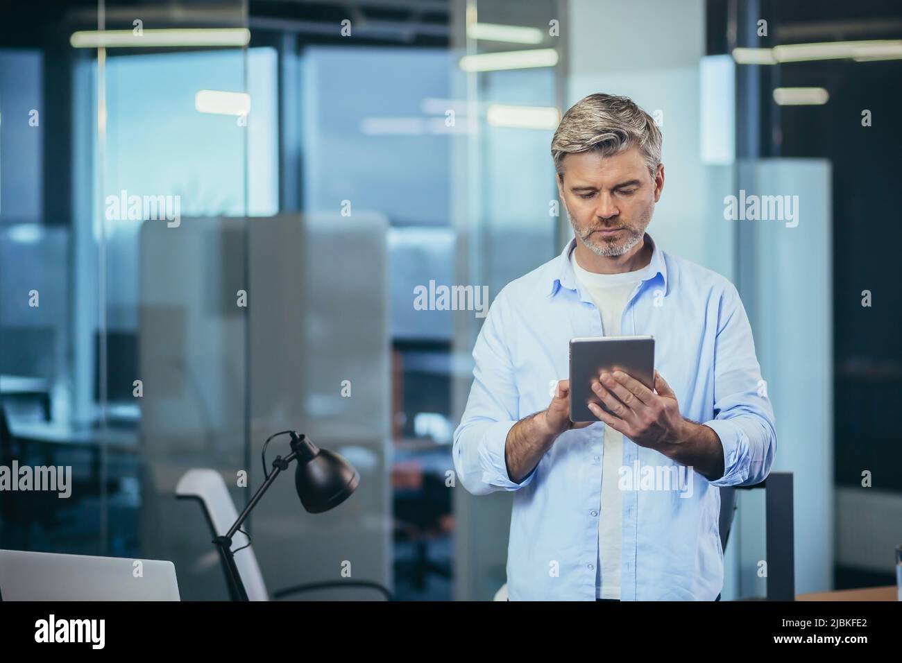 Il proprietario di affari riuscito e premuroso usa un calcolatore del tablet, uomo d'affari lavora in un ufficio moderno Foto Stock