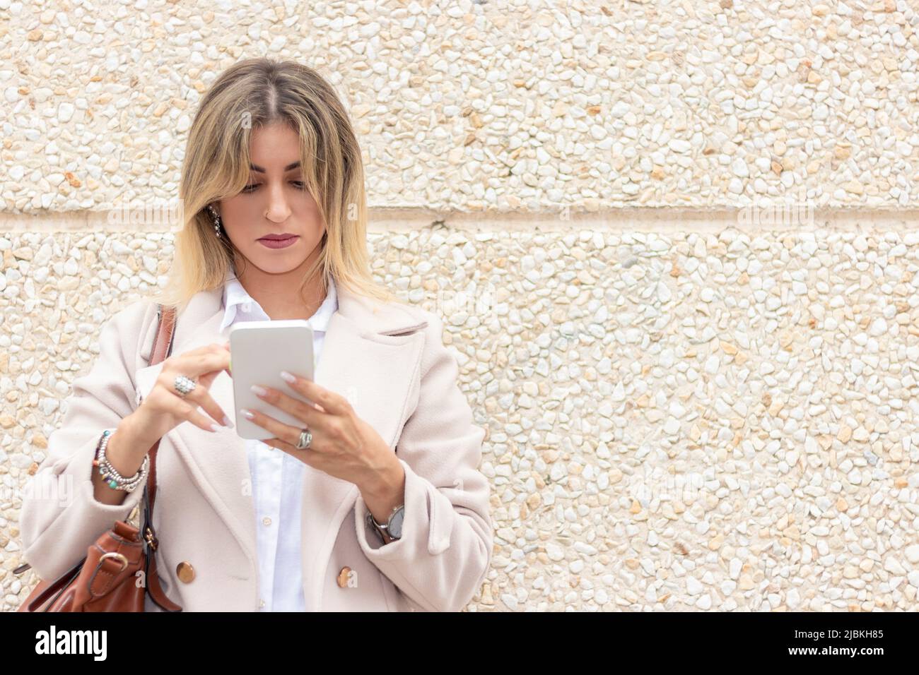 moderna giovane donna d'affari appoggiata su una parete guardando mobile Foto Stock