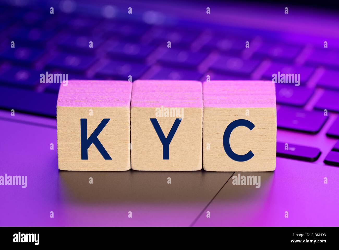 KYC parola su blocchi di legno su computer portatile con luci colorate. Concetto di conoscenza del cliente online Foto Stock