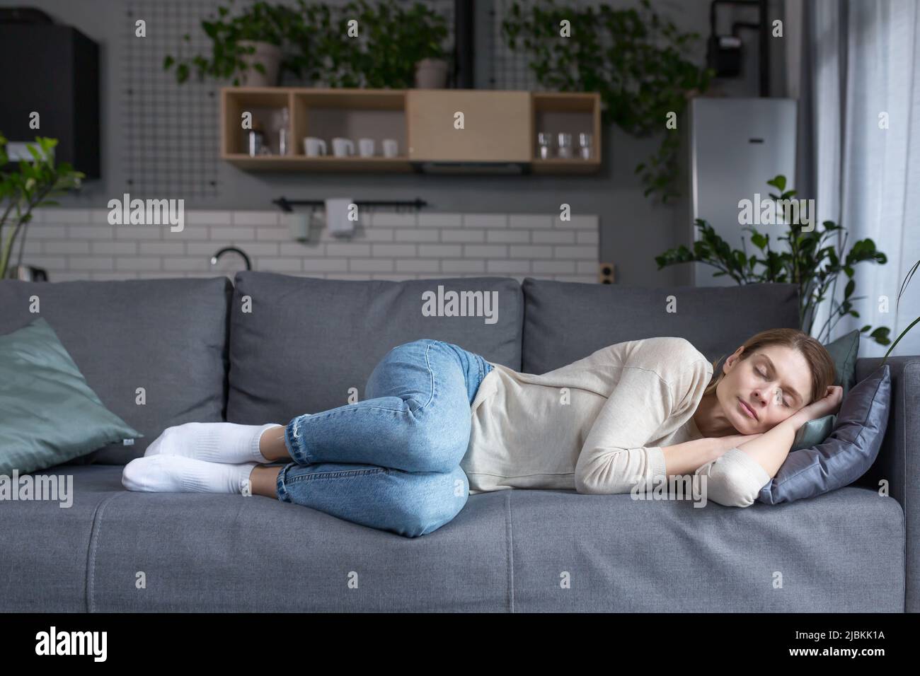 Donna bionda stanca di mezza età che dorme sul divano dopo il lavoro Foto Stock