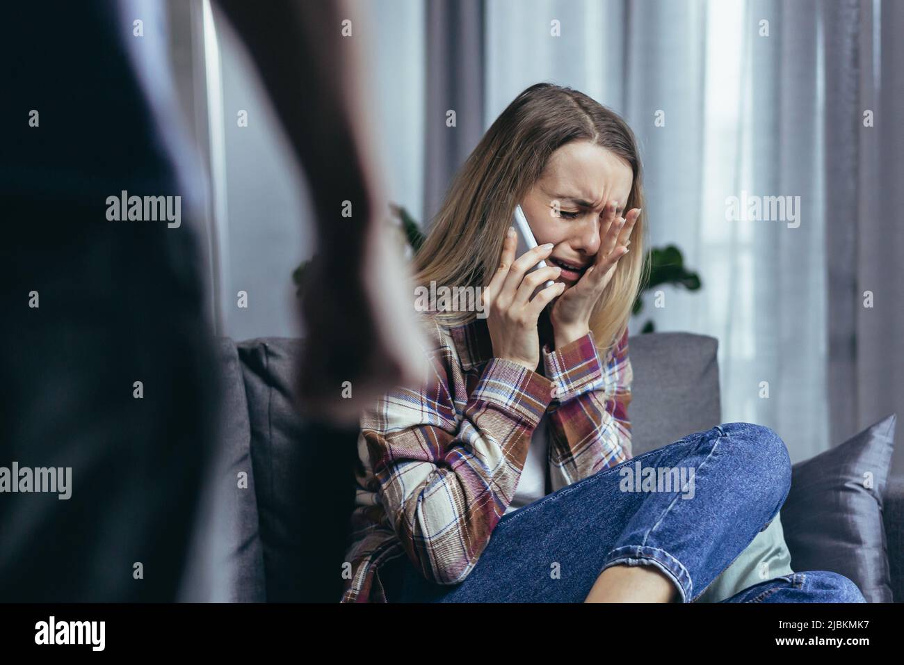 Conflitto in famiglia, il marito litigato batte la donna e grida, la moglie si siede sul divano e grida, chiama la polizia chiede aiuto Foto Stock