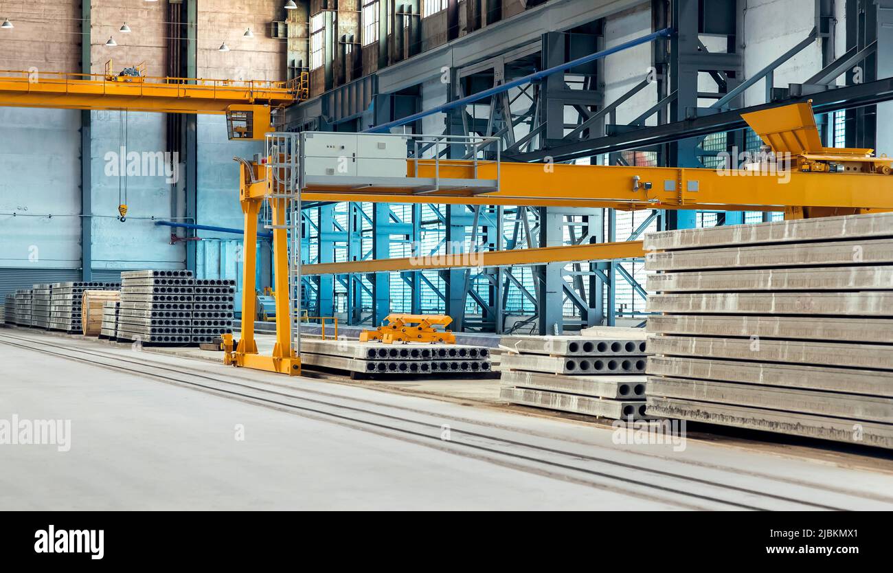 stabilimento industriale per la produzione di lastre di pavimenti impilate in pile in officina con attrezzature automatizzate e trave carroponte gialla, magazzino di pre Foto Stock