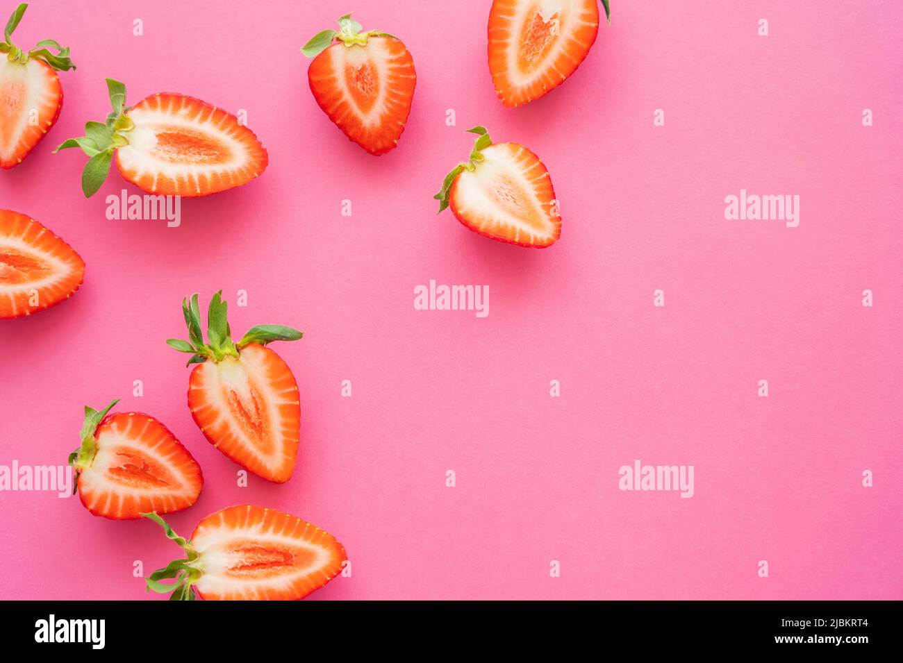 Piatto posato con metà di fragole su sfondo rosa Foto Stock
