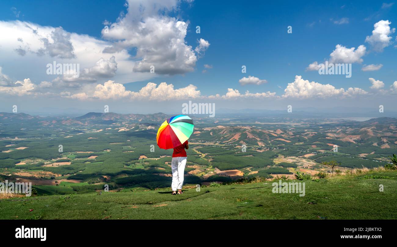Chu Tan Kra Peak nel distretto di SA Thay, provincia di Kon Tum, Vietnam - 24 aprile 2022: Una femmina turistica che tiene un ombrello colorato si erge per ammirare il sc Foto Stock