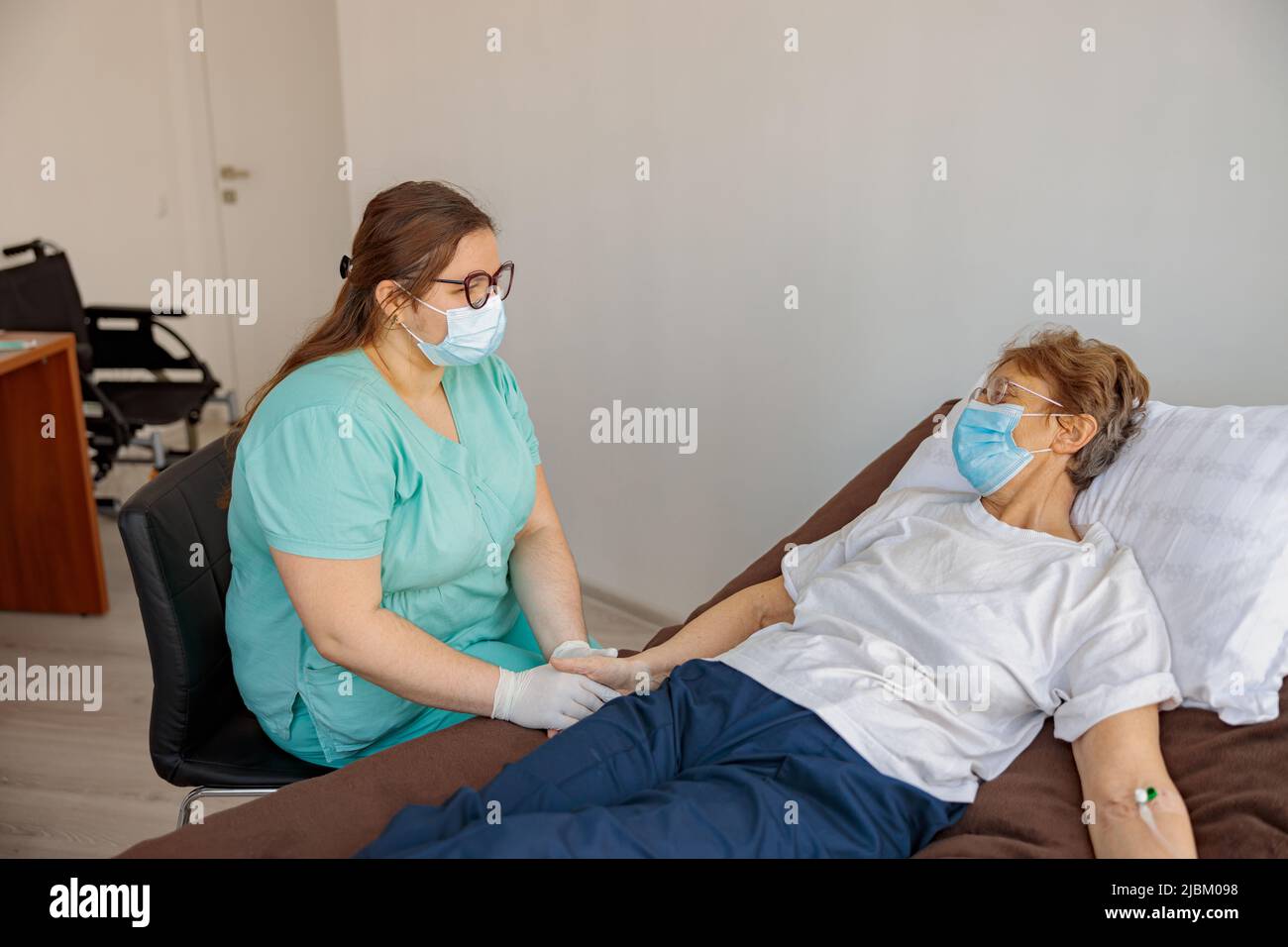 L'infermiere professionale controlla il gocciolamento del paziente nella clinica di medicina moderna Foto Stock