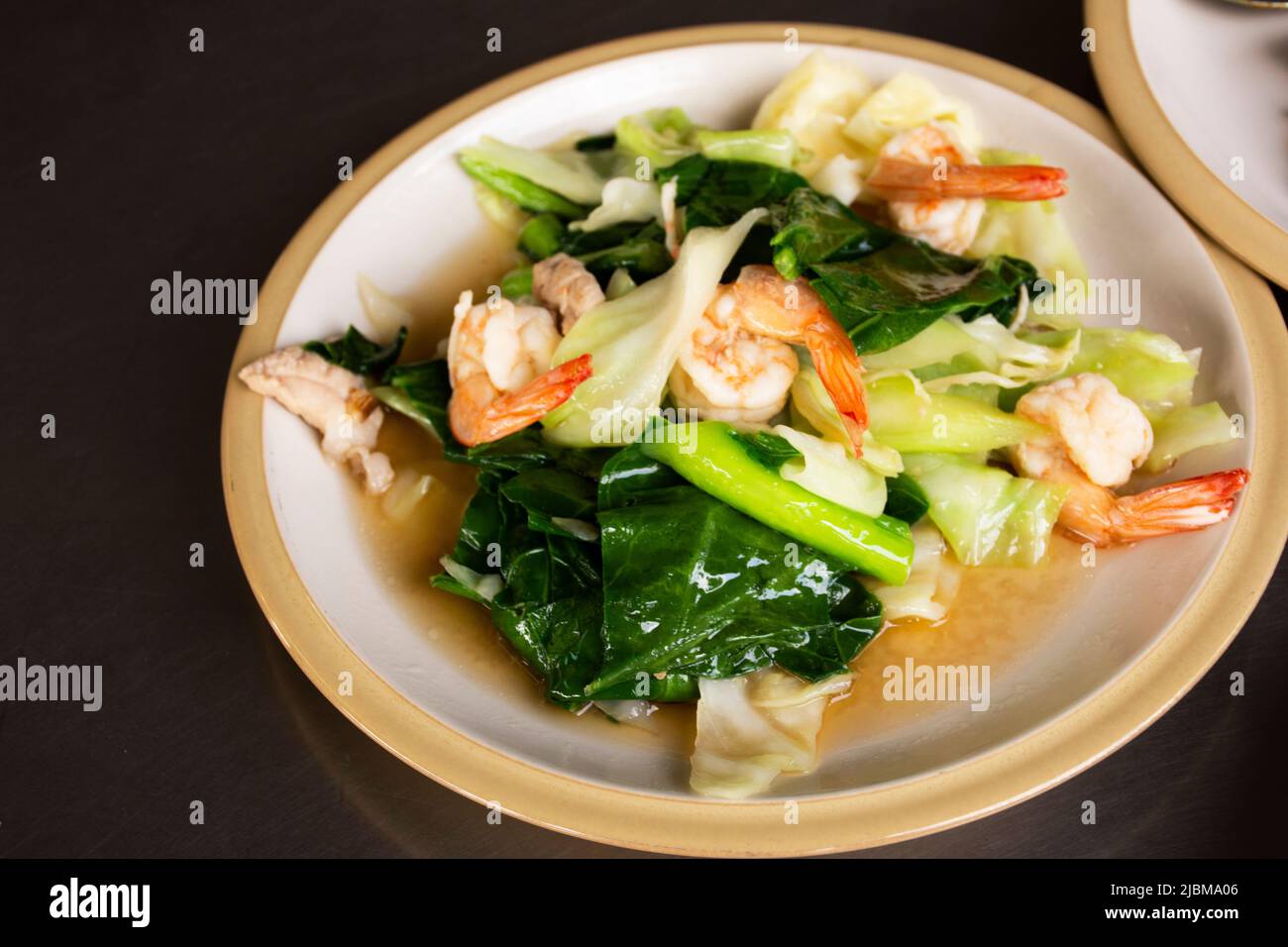 Street food tradizionale cucina tailandese locale gamberetti fritti con kale cinese o Stir fry gai lan e gamberi su piatto per la gente servita cliente Foto Stock
