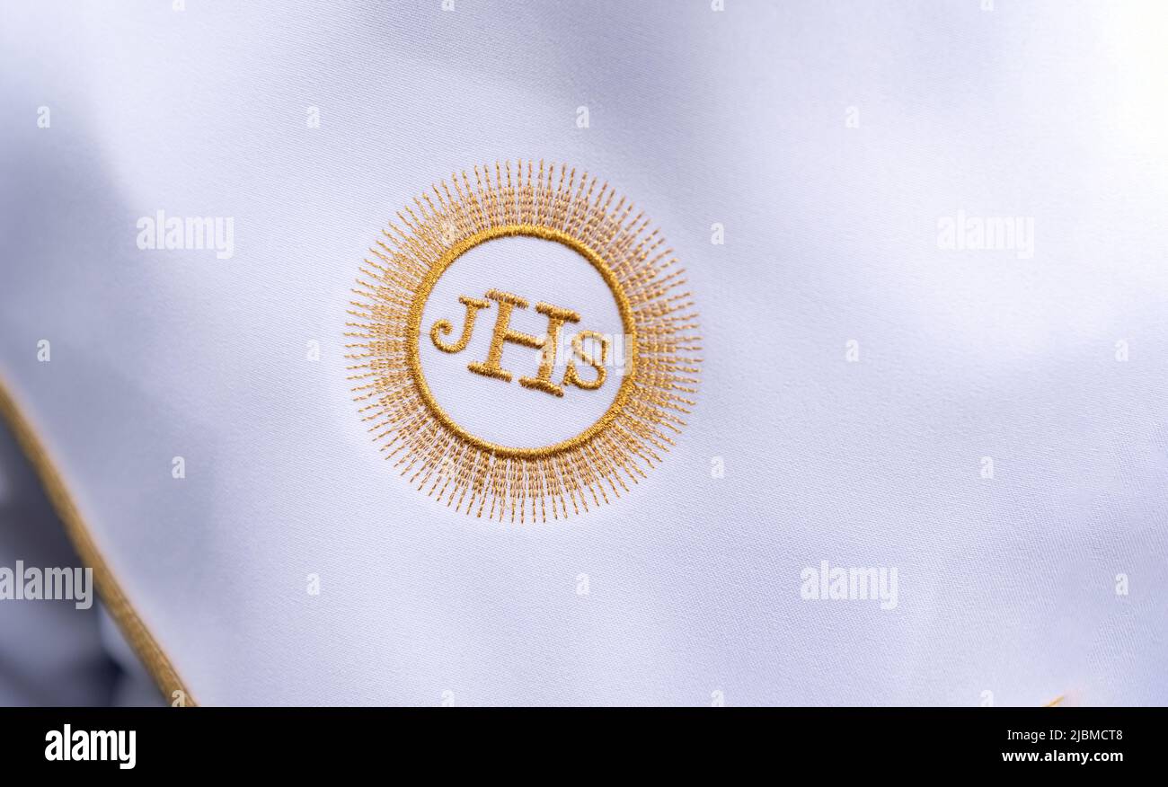 IHS simbolo cristiano su un bambino di comunione. IHS Christogram ricamato con filo d'oro su un'erba bianca. Primo vestito della Santa comunione. Foto Stock
