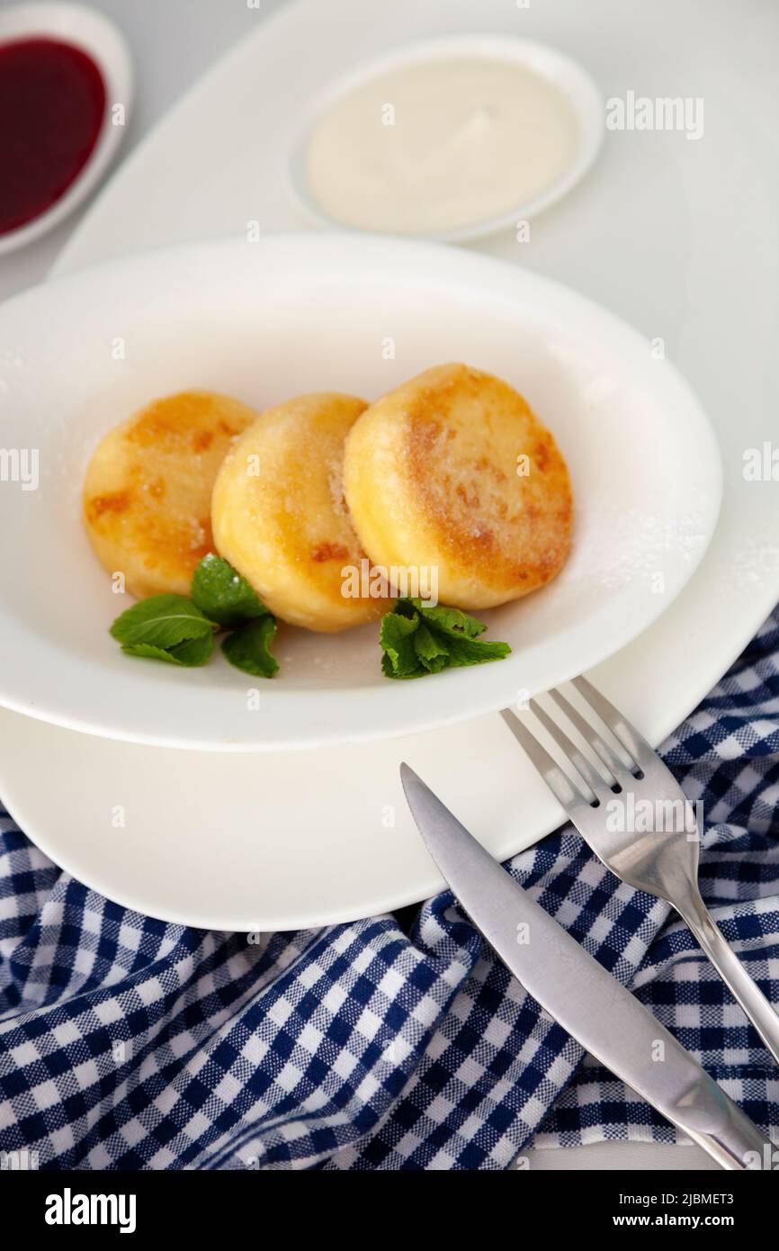 Una porzione di tre pancake rotondi di formaggio cagliato su un piatto bianco. Colazione sana. Sfondo alimentare. Spazio di copia. Foto Stock