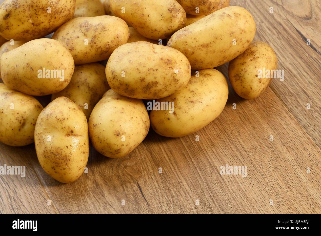 Un mucchio di patate su un asse di legno Foto Stock