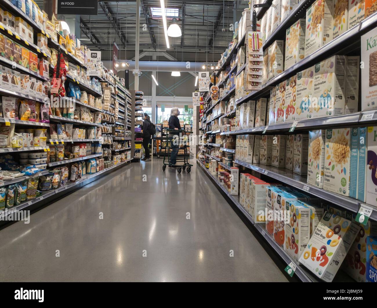 Kirkland, WA USA - circa Settembre 2021: Vista ampia di una donna anziana che acquista nella corsia dei cereali e dei granoli all'interno di un intero mercato alimentare. Foto Stock Kirkland, WA USA - circa Settembre 2021: Vista ampia di una donna anziana che acquista nella corsia dei cereali e dei granoli all'interno di un intero mercato alimentare. Foto Stock