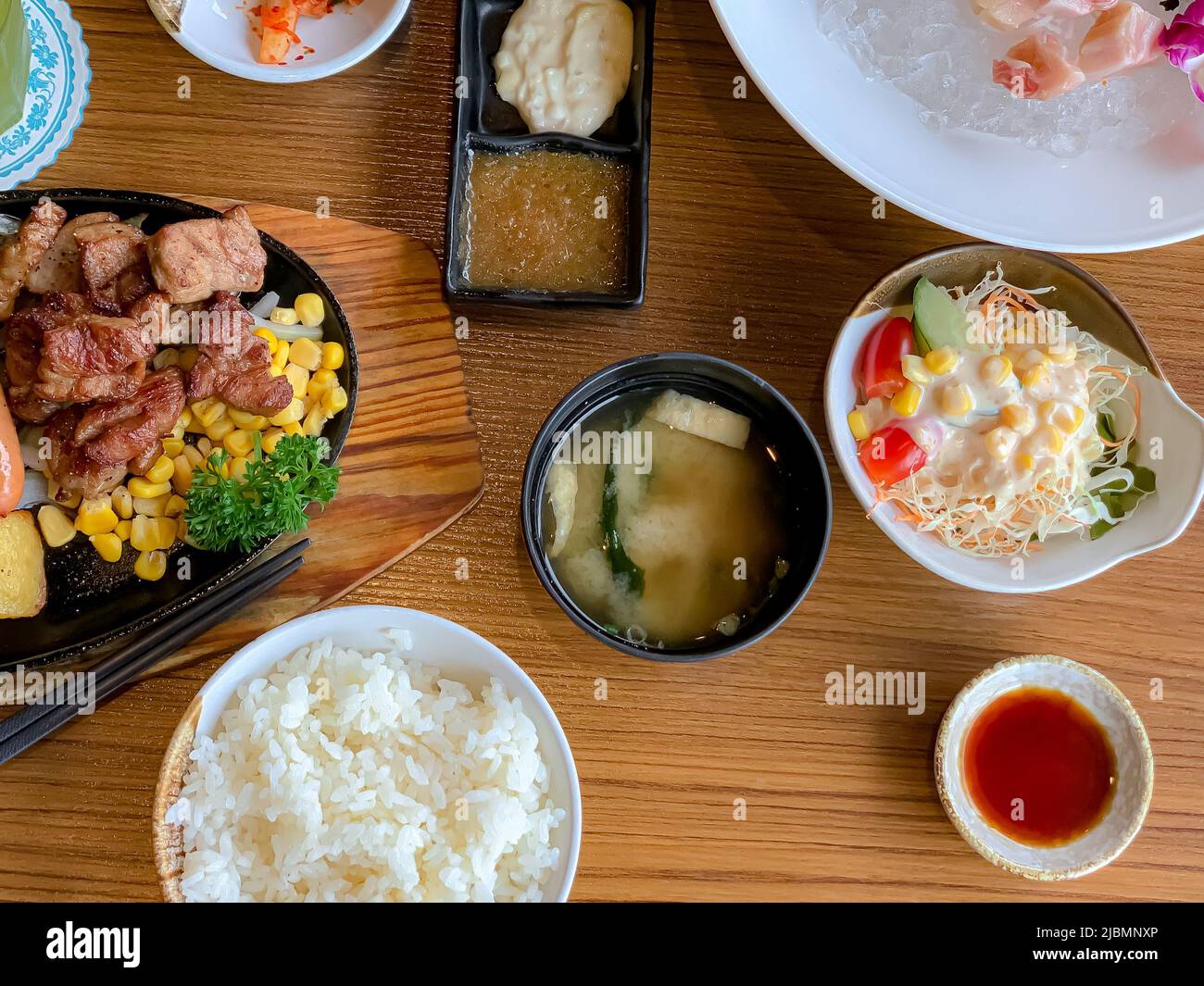 Menu vari, sushi, sashimi, nigiri, maiale fritto in padella e zuppa di miso. Sashimi, chutoro sashimi, bacchette alimentari giapponesi e wasabi sul tavolo nero, Foto Stock