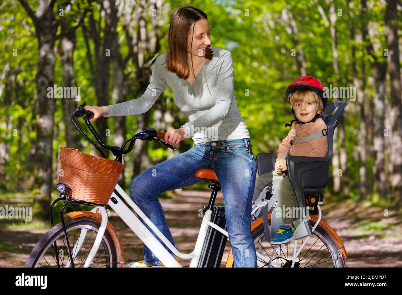 Madre con ragazzo biondo su e-bike sul sedile posteriore Foto Stock