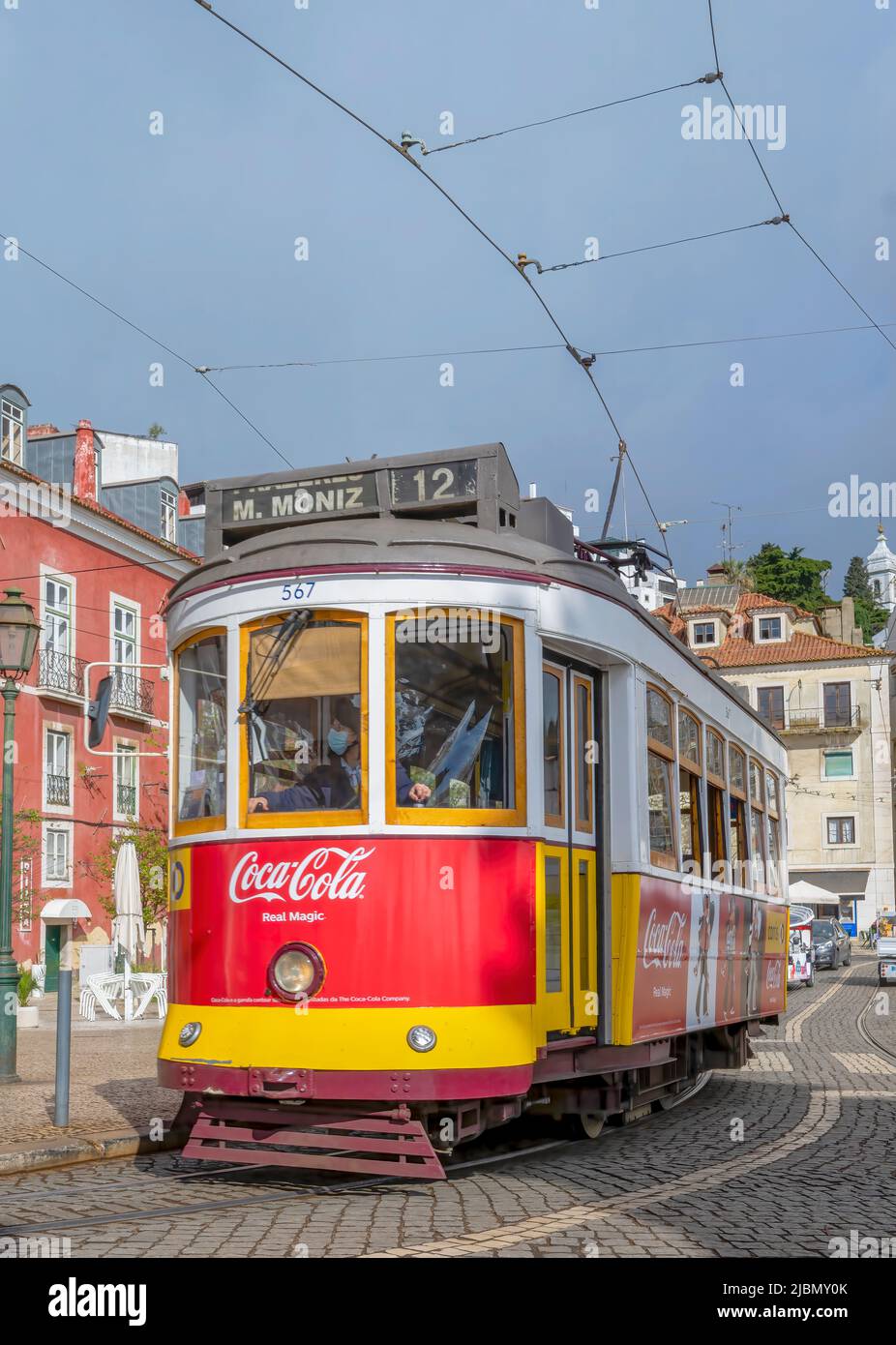 Un tradizionale tram rosso negozia le strade bagnate e acciottolate nel centro di Lisbona, capitale del Portogallo Foto Stock