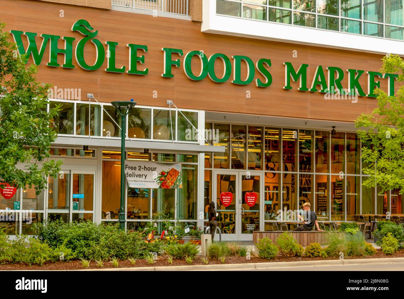 La facciata esterna di Whole Foods Market è contraddistinti da un marchio e da un logo in lettere verdi su sfondo di legno con finestre in vetro, porte in vetro e verde. Foto Stock