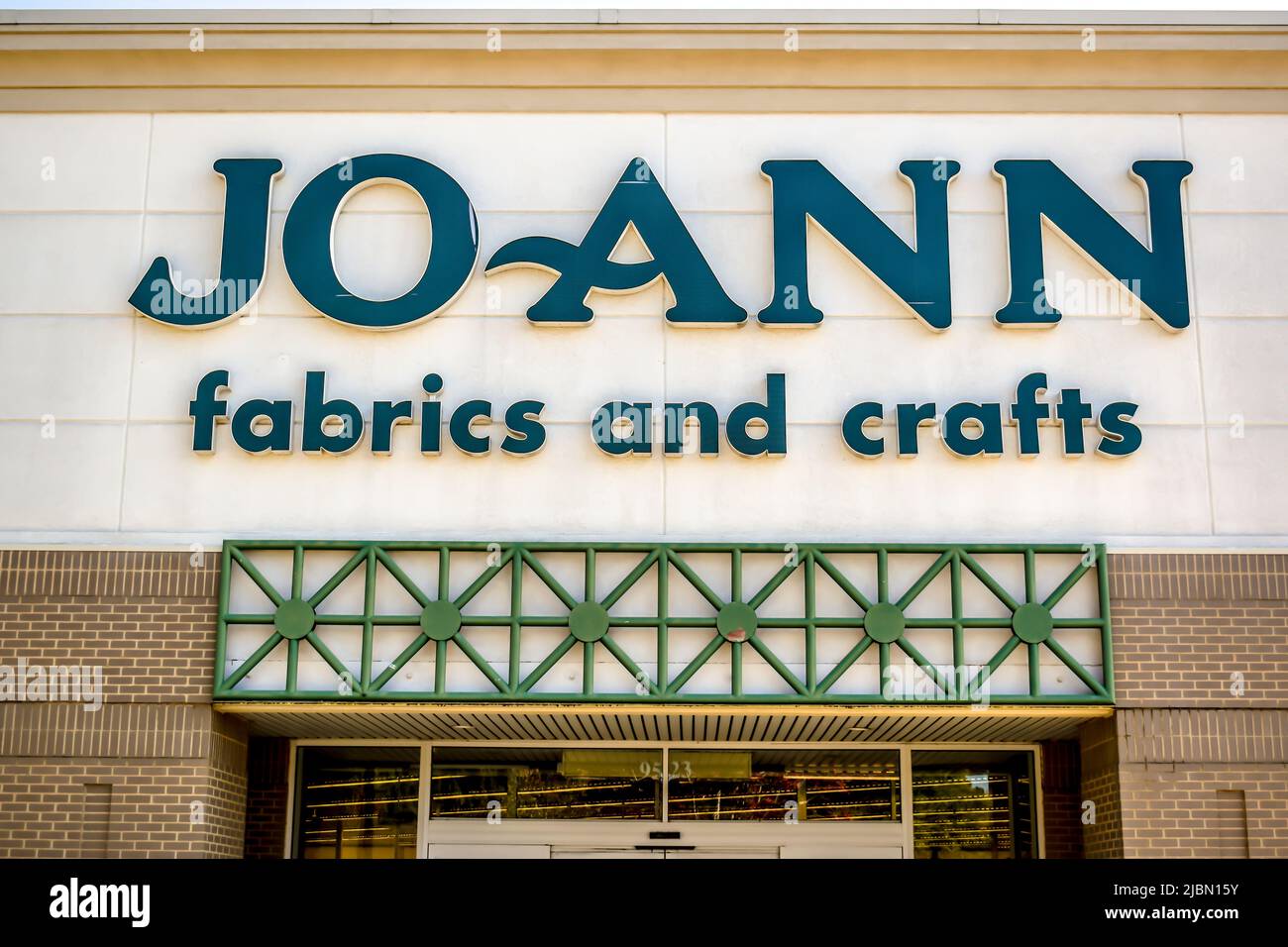 JoAnn tessuti e artigianato negozio di facciata esterna marchio e logo in lettere scure, verde teale su beige sopra finestre di vetro e finiture marrone chiaro. Foto Stock