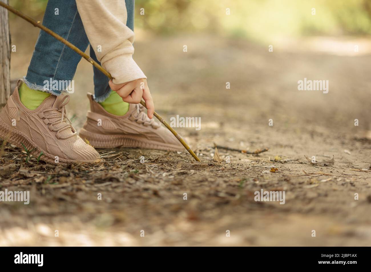 La bambina dipinge a terra con bastone all'aria aperta nel parco delle fiabe in fiore in primavera. Foto di alta qualità Foto Stock