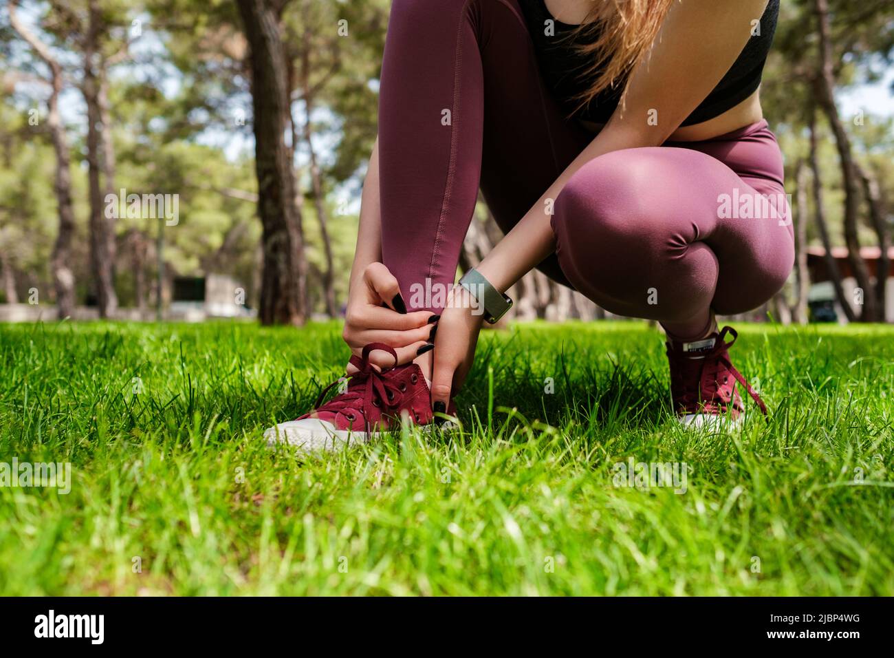 Giovane donna bruna che indossa abiti sportivi nel parco cittadino, all'aperto che soffre di una lesione alla caviglia durante l'esercizio e la corsa. Sanità e sport Foto Stock