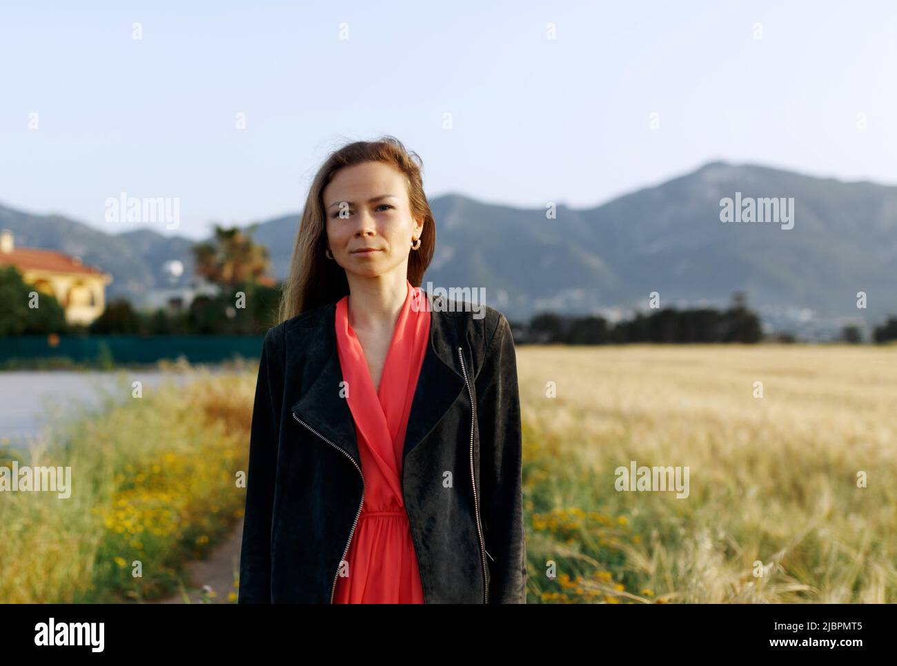 Donna seria matura in autunno con giacca di fronte ad un campo di fiori. Foto Stock