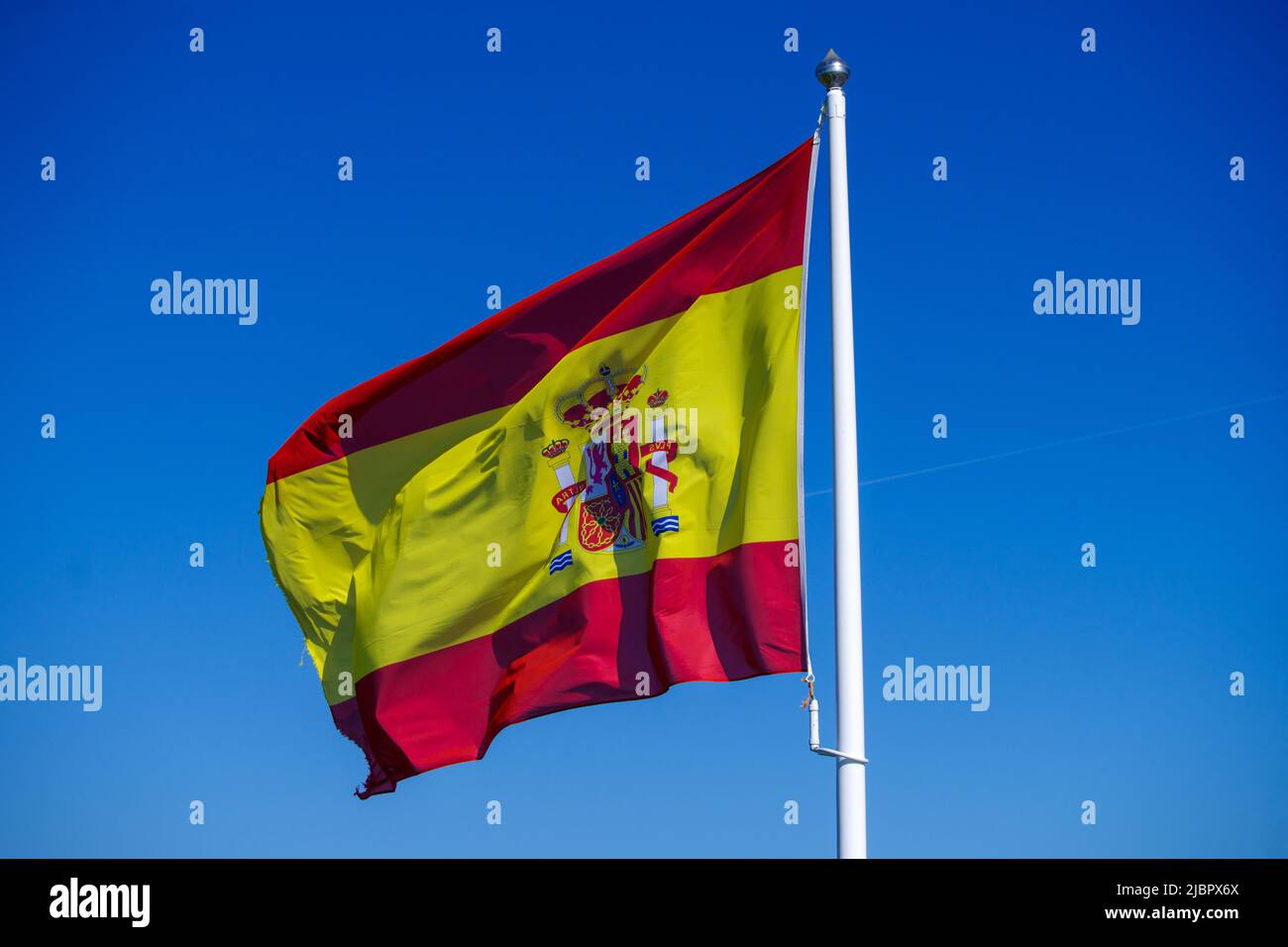 Bandiera nazionale della Spagna che vola al vento di fronte al cielo azzurro Foto Stock