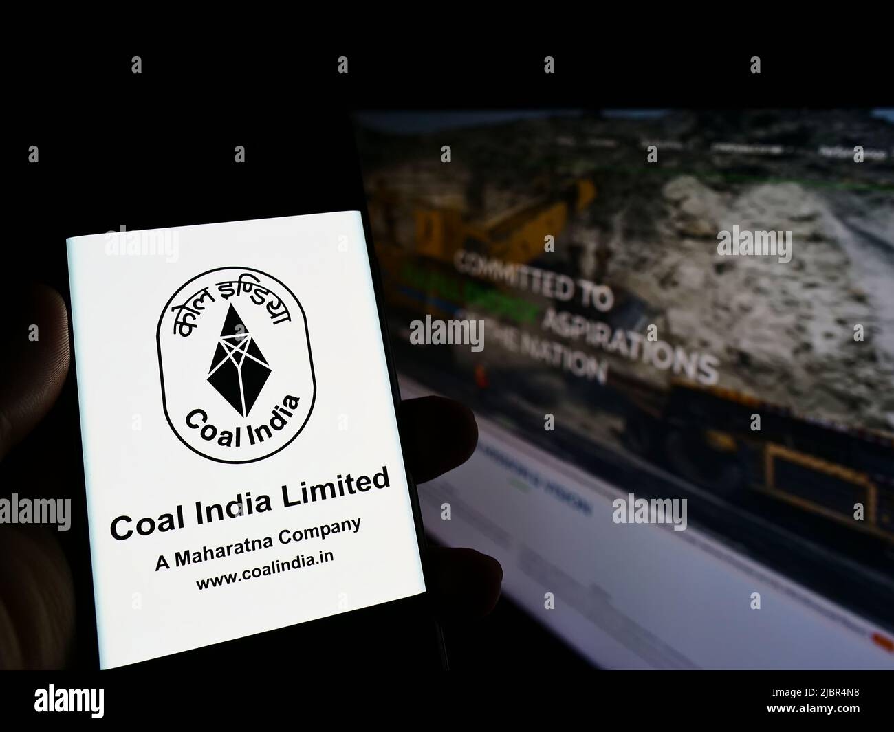 Persona che tiene smartphone con il logo della società mineraria Coal India Limited (CIL) sullo schermo di fronte al sito web. Mettere a fuoco sul display del telefono. Foto Stock