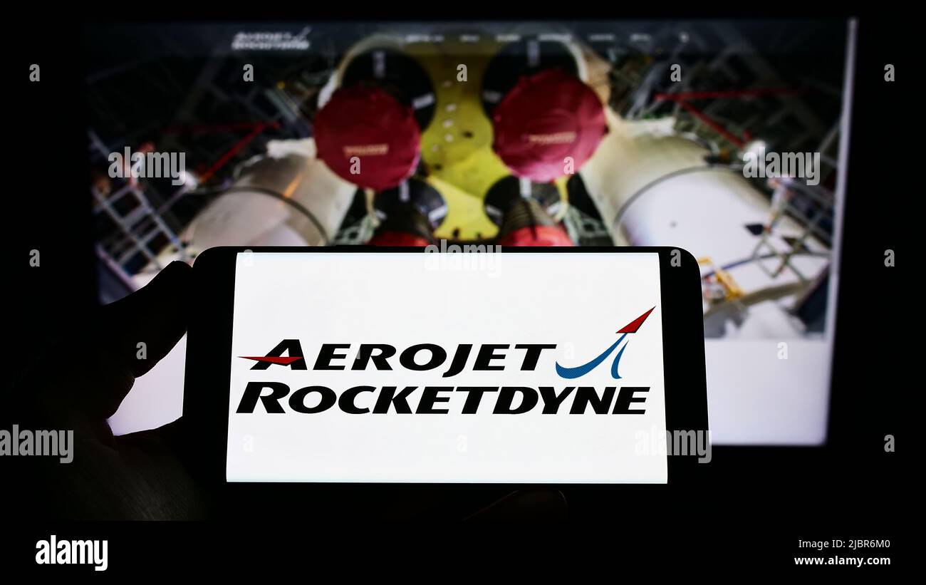 Persona che tiene uno smartphone con il logo della società aerospaziale statunitense Aerojet Rocketdyne sullo schermo di fronte al sito web. Mettere a fuoco sul display del telefono. Foto Stock